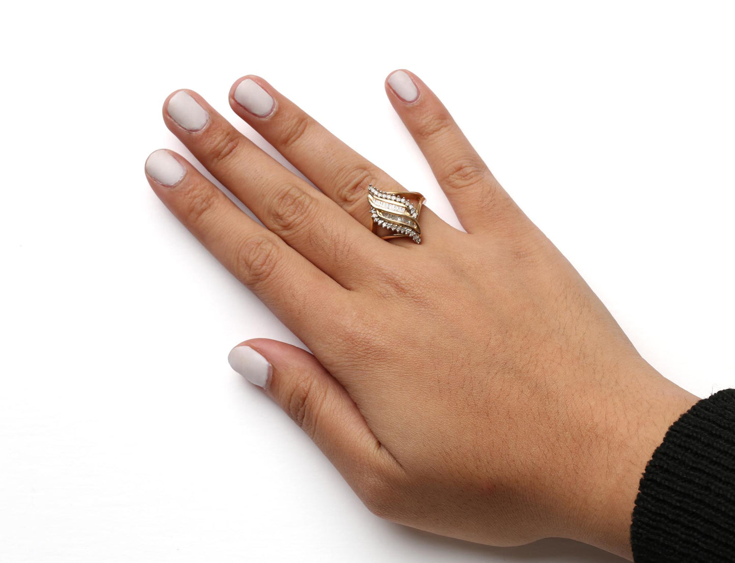 Close-up of a yellow metal ring with white round prong-set gemstones and white baguette channel-set gemstones, worn on a model's hand, shot from above.