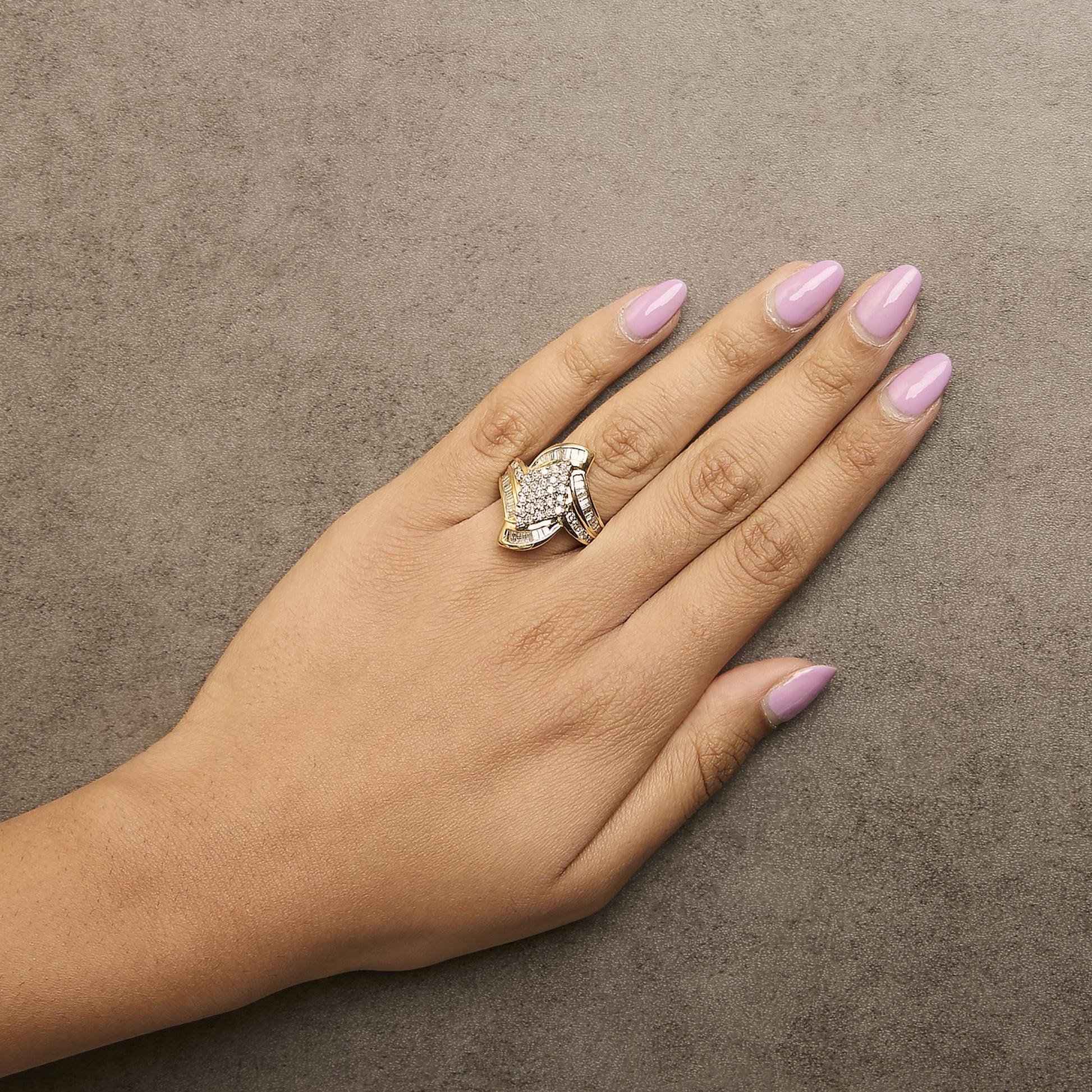 Yellow metal ring with cluster of round white gemstones in prong setting at center, surrounded by bands of channel-set white baguette gemstones, shown worn on a hand, top view.