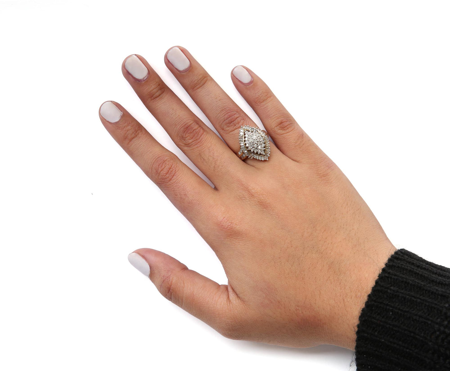 Yellow metal ring with round and baguette white gemstones in prong settings, worn on a model's hand, shown from top angle.