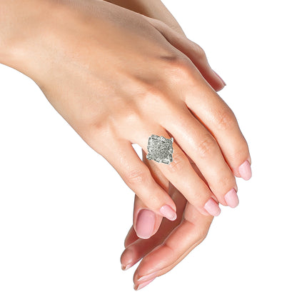 White metal ring with round white gemstones in prong setting and baguette white gemstones in channel setting, worn on a model's hand shown from a top side angle.