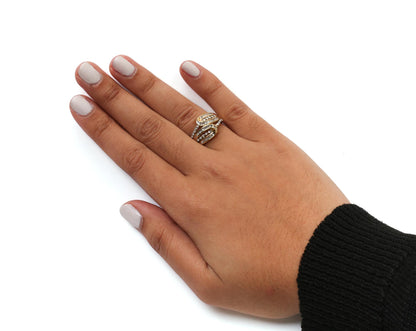 Yellow metal ring with white round prong-set gemstones and white baguette channel-set gemstones, worn on hand, top down angle.