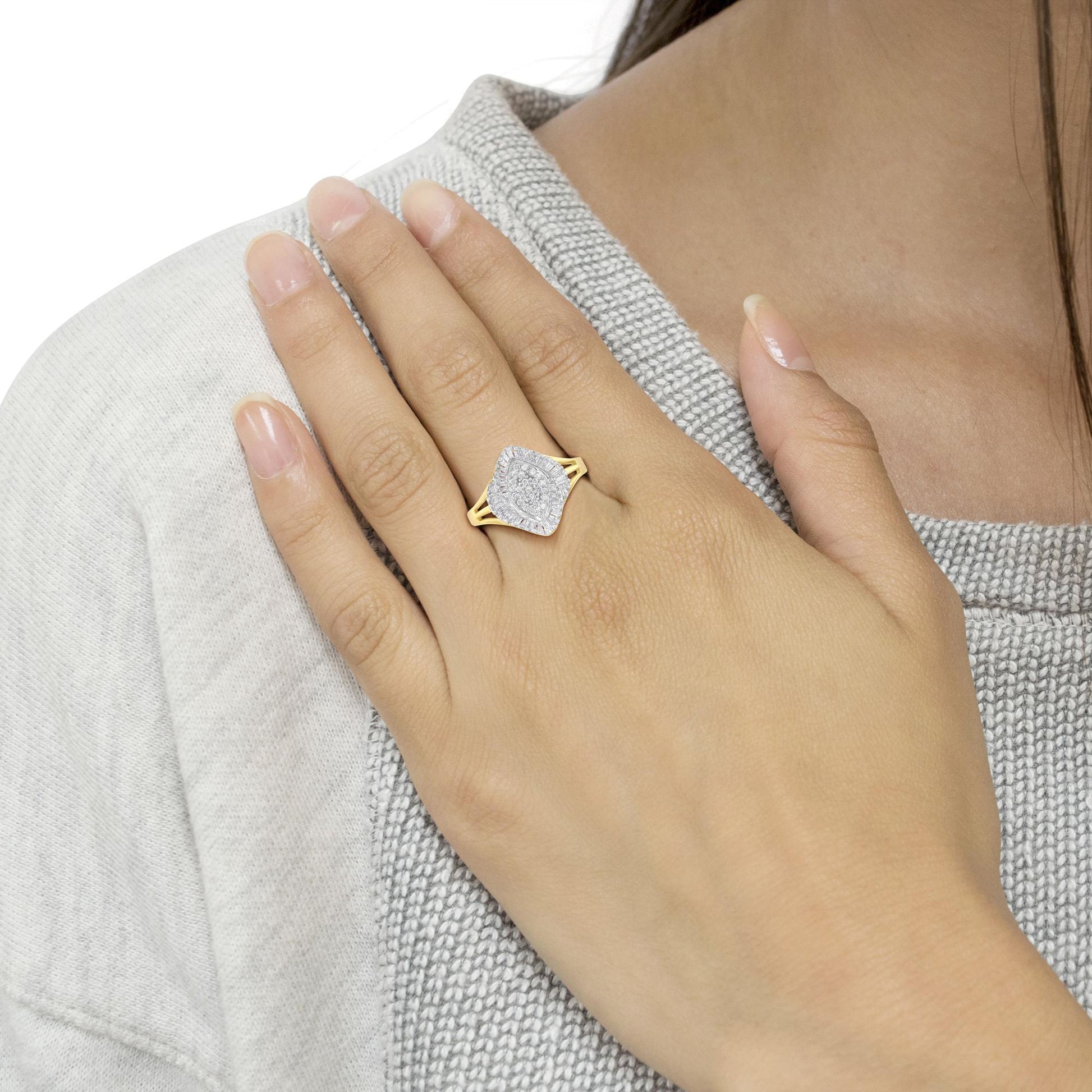 Close-up angled view of a yellow ring with round white gemstones in prong setting and baguette white gemstones in channel setting, worn on a model's finger.