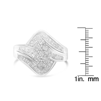 Front angle of a white ring with round prong-set white gemstones clustered in the center and baguette channel-set white gemstones outlining the front design, shown next to a ruler for size reference.