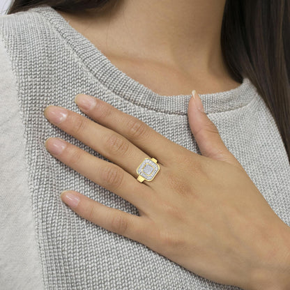 Close-up of a yellow metal ring with round prong-set white gemstones in the center, surrounded by baguette channel-set white gemstones, worn on a model's hand.