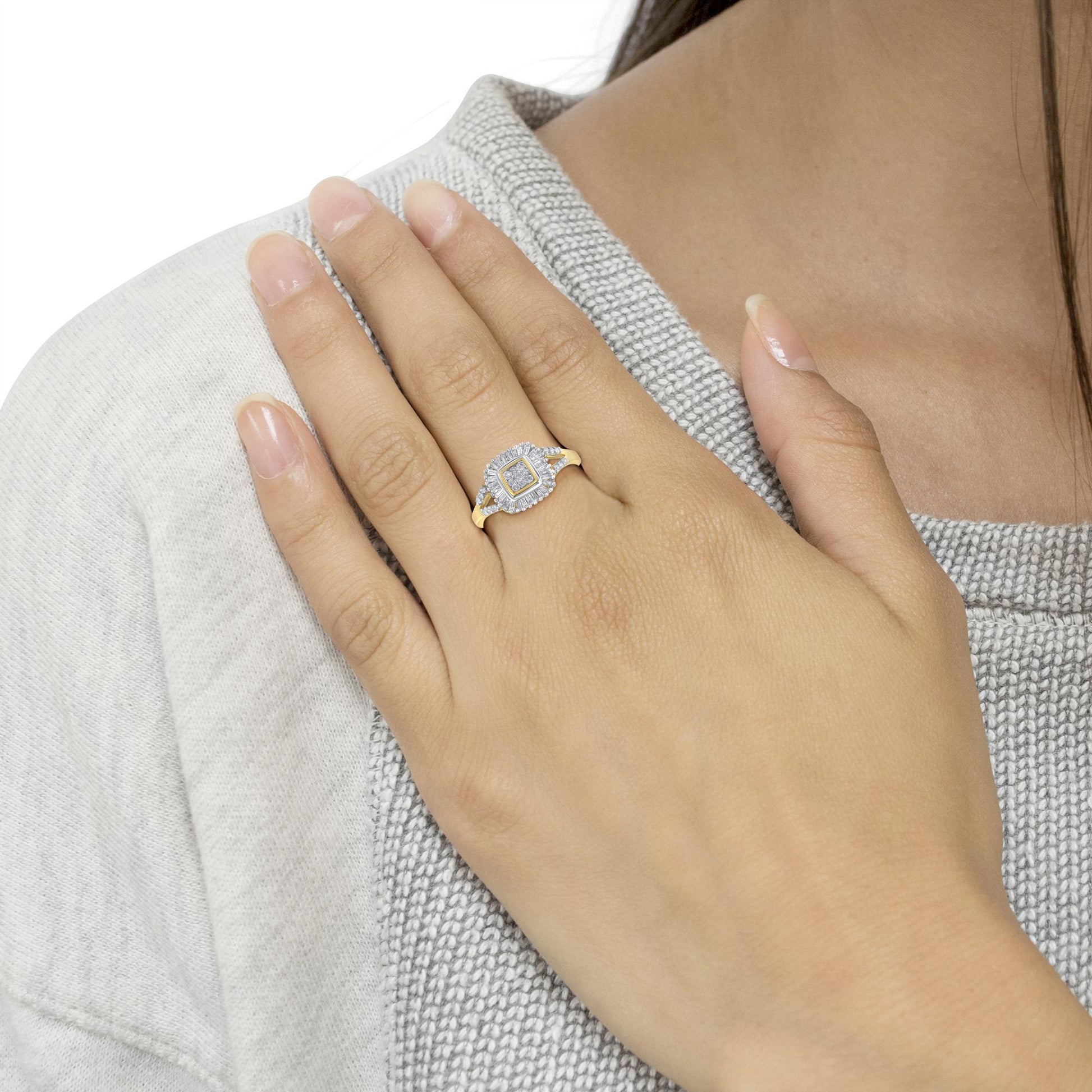 Yellow metal ring with round and baguette white gemstones, prong and channel set, shown on a model's hand from a top angle.