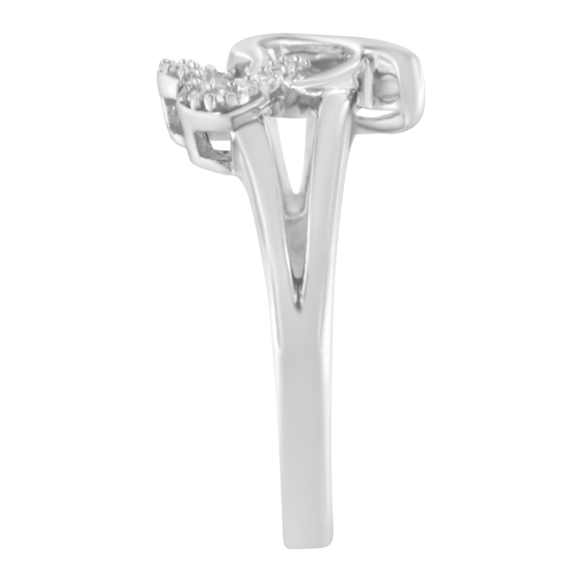 Side angle view of a white metal ring with a split shank and round white gemstones in a prong setting on the top.