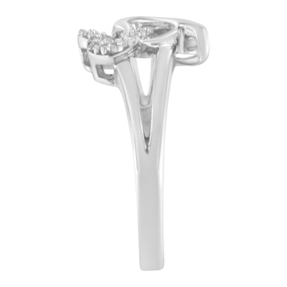 Side angle view of a white metal ring with a split shank and round white gemstones in a prong setting on the top.