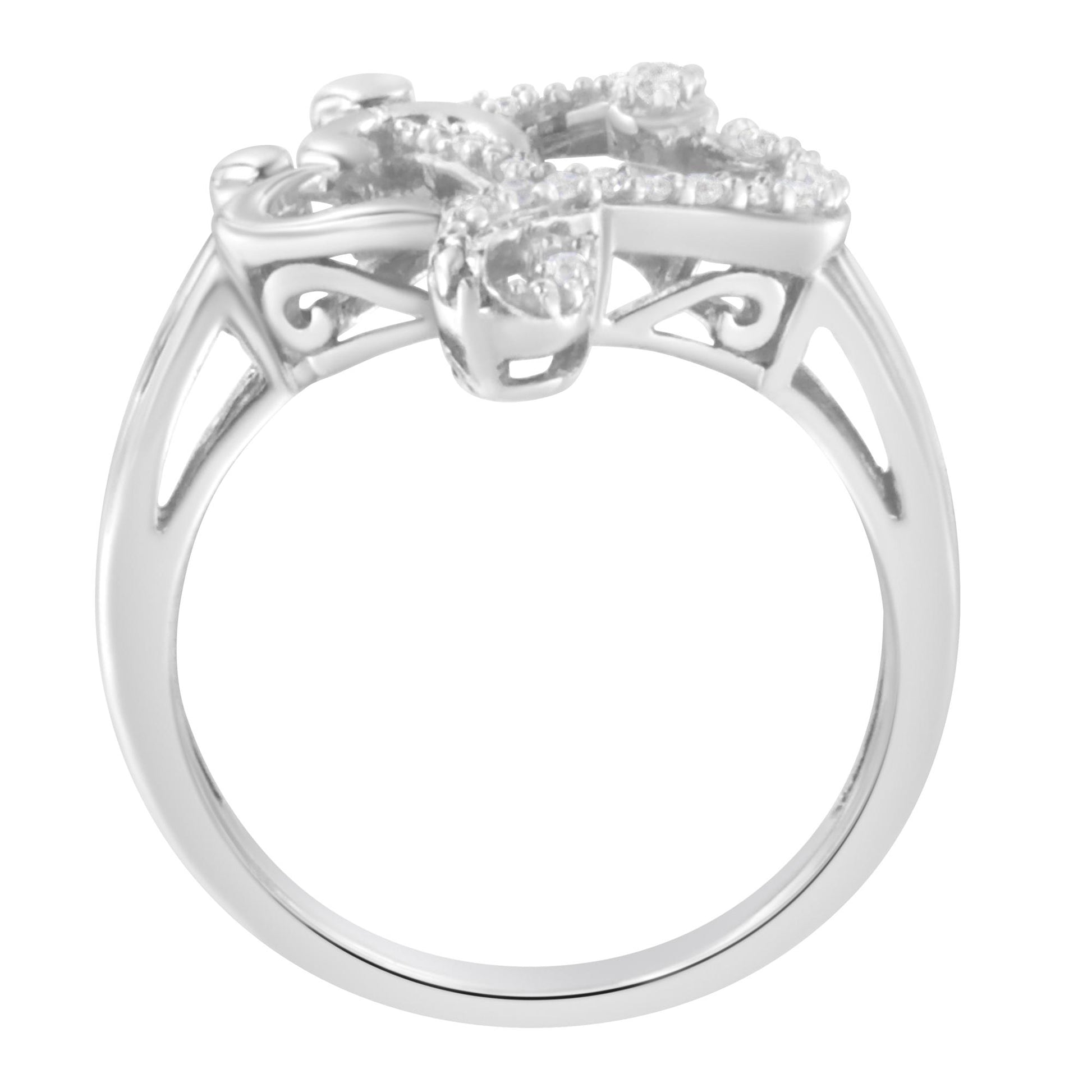 White metal ring with ornate scrollwork and round white gemstones in a pave setting, shown from a front angle.
