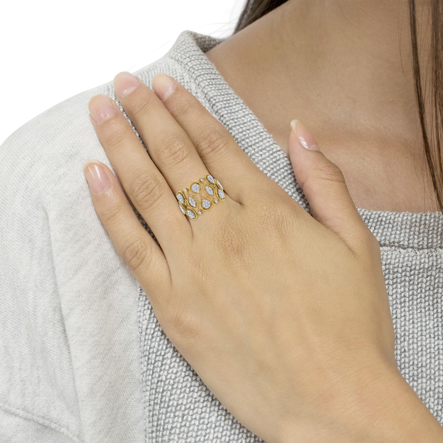 Close-up shot of a yellow ring with white round gemstones in pave setting, worn on a model's finger.