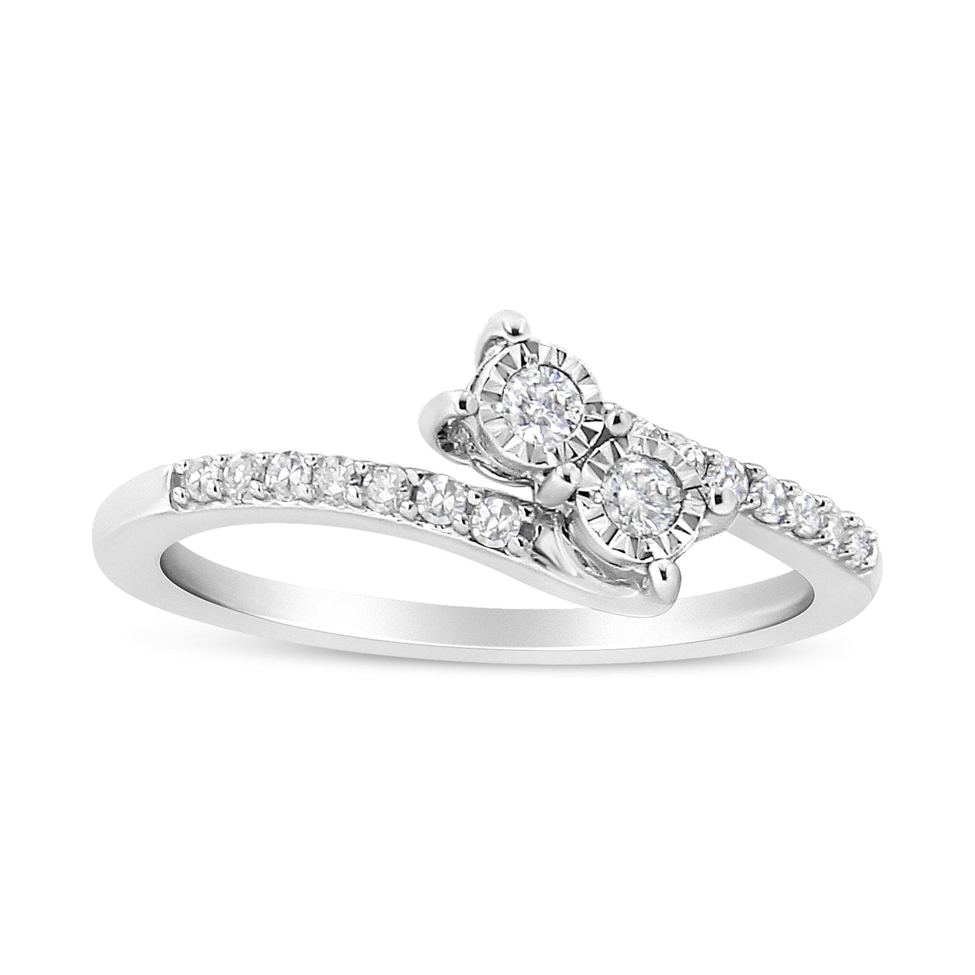 White metal ring shown at an angle with a bypass design featuring two round white gemstones in miracle settings and a band accented with smaller round white gemstones in prong settings.