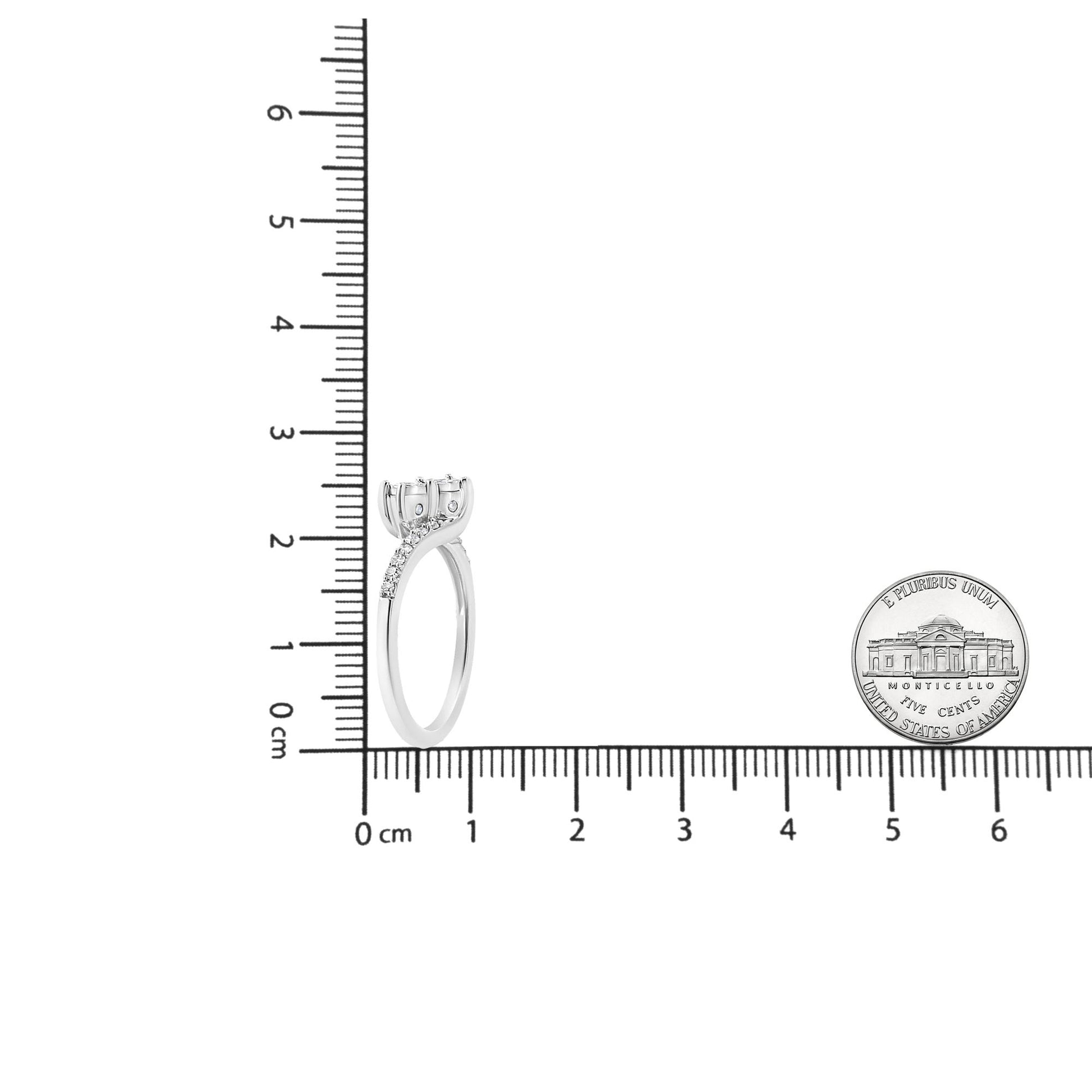 White metal ring with two round white gemstones in a miracle setting and multiple smaller round white gemstones in a prong setting along the band, photographed upright on a ruler for size reference.