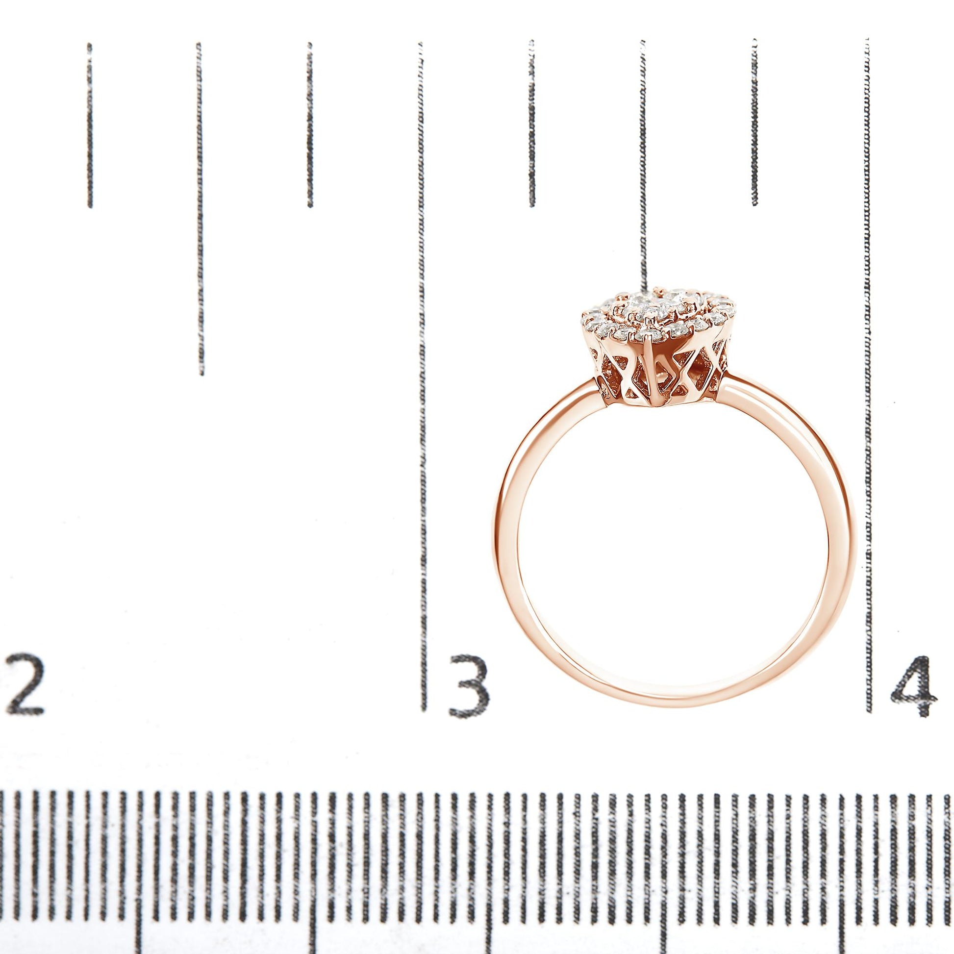 Rose metal ring with round white gemstones in prong setting viewed from the side, placed on a ruler for size reference.