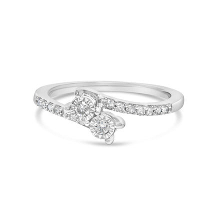 Close-up angle of a white metal ring featuring two round white gemstones in miracle settings and additional small round white gemstones in shared prong settings along the band.