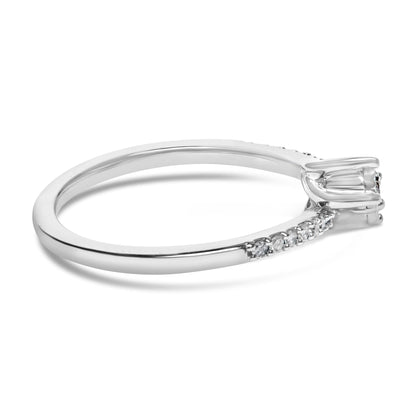 Close-up side angle of a white ring featuring two round white gemstones in miracle setting and additional round white gemstones in shared prong setting along the band, shown on a white background.