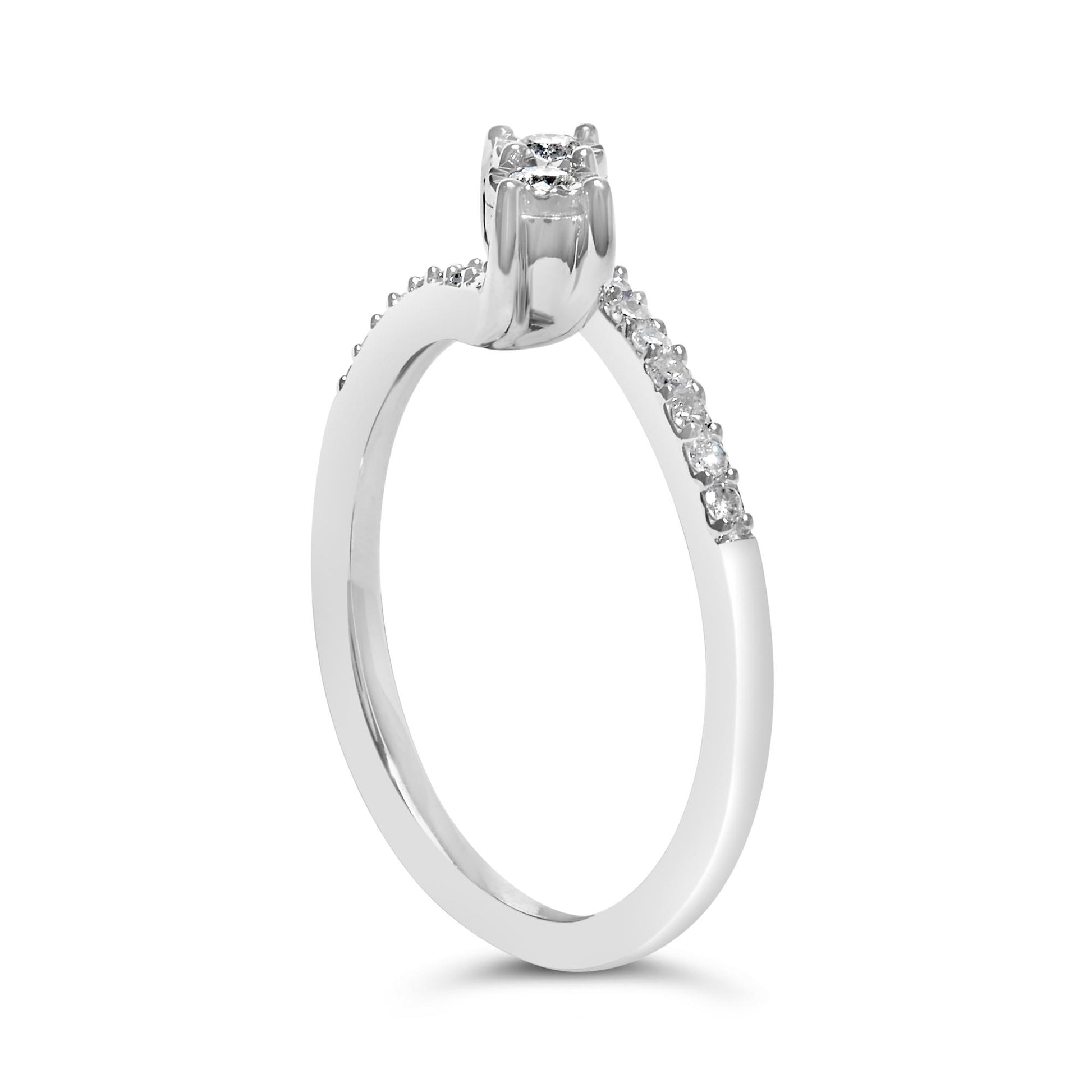 Close-up front angle of a white ring featuring two round white gemstones in a raised setting, and multiple smaller round white gemstones in a shared prong setting along the band.