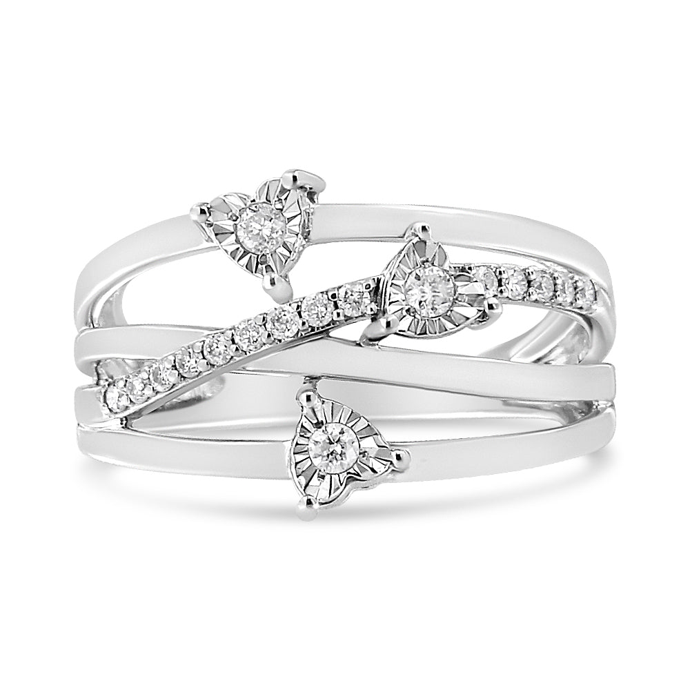 Front angle view of a white ring with three heart-shaped settings each holding a round white gemstone in miracle setting and a diagonal row of round white gemstones in prong setting across the band.