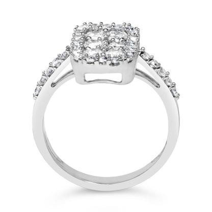 Front-facing close-up of a white metal ring with a square cluster of round white gemstones in prong settings on top and additional round white gemstones set along the shoulders.