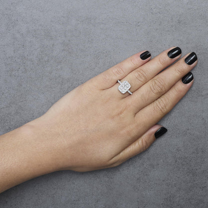 White metal ring with a cluster of round white gemstones in prong settings on a model's hand, shown from above.