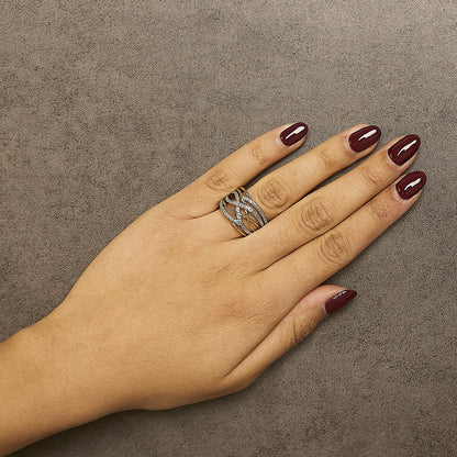 Close-up angled shot of a yellow metal ring with intertwined bands featuring white round gemstones in a pave setting, worn on a model's finger.