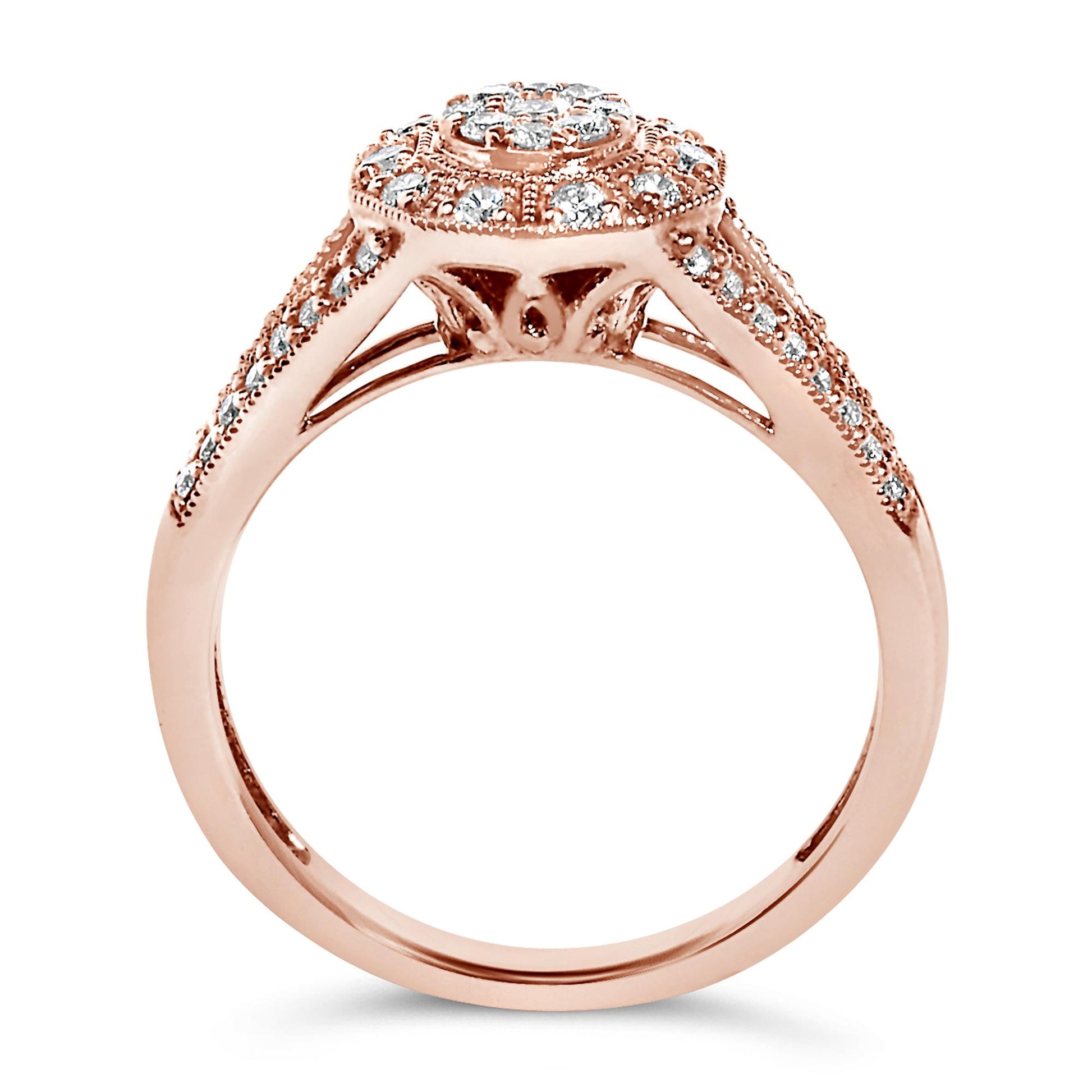 Side angle close-up of a rose-colored ring with a round center white gemstone surrounded by smaller white gemstones in a pave setting, also featuring additional white gemstones along the band.