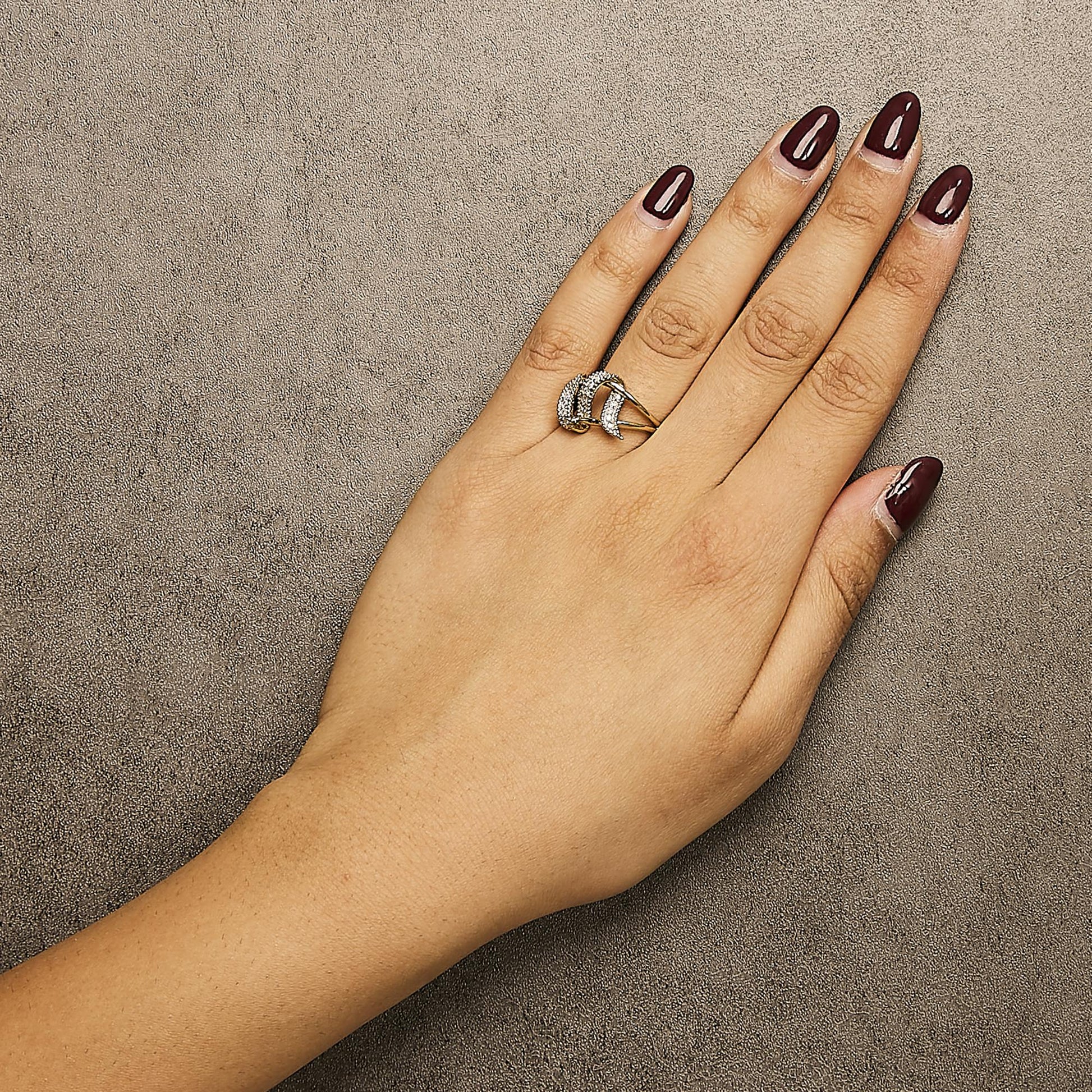 Yellow metal ring with three curved bands adorned with pave-set white round gemstones, shown on a model's hand from a top-down angle.
