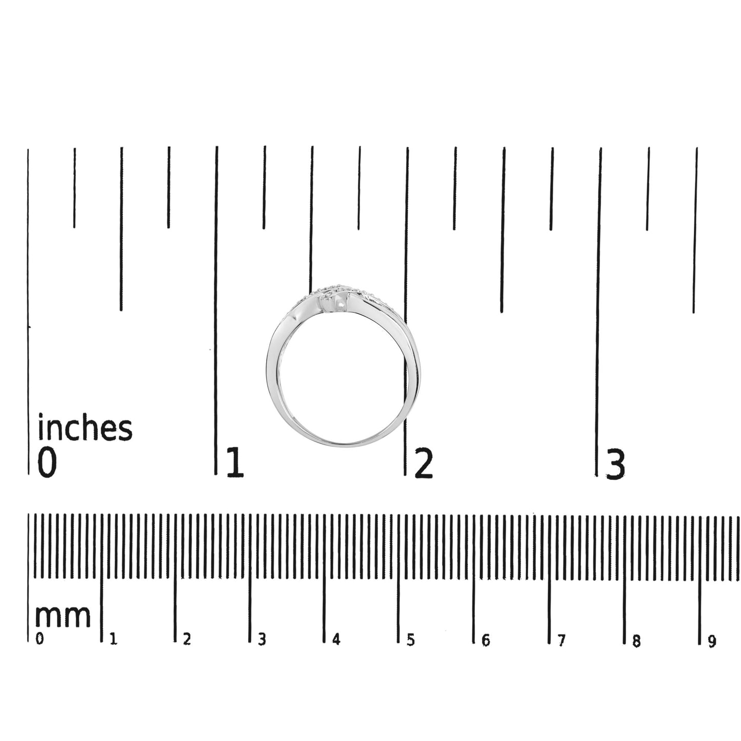 White metal ring with round white gemstones in prong settings, viewed from the side, positioned on a ruler for size reference.