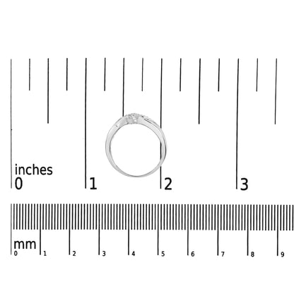 White metal ring with round white gemstones in prong settings, viewed from the side, positioned on a ruler for size reference.