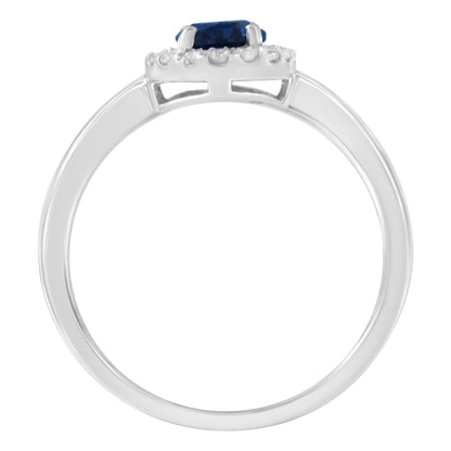 Side view of a white metal ring featuring an oval-shaped blue gemstone in a prong setting, surrounded by multiple round white gemstones also in prong settings.