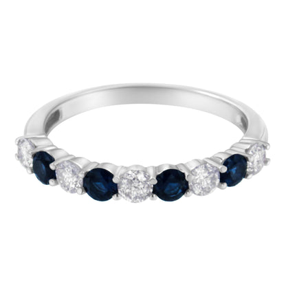 White metal ring with alternating round white gemstones and blue gemstones in prong settings, shown in a close-up front angle.
