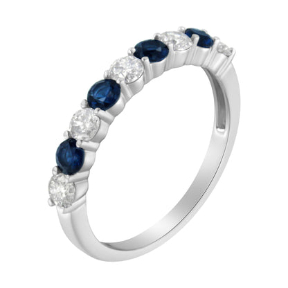 White metal ring with alternating round white and blue gemstones in prong settings, shown at an angle.