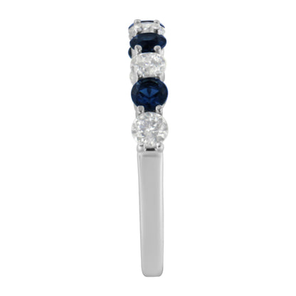 Side view of a white metal ring featuring alternating round white gemstones and blue gemstones in prong settings.