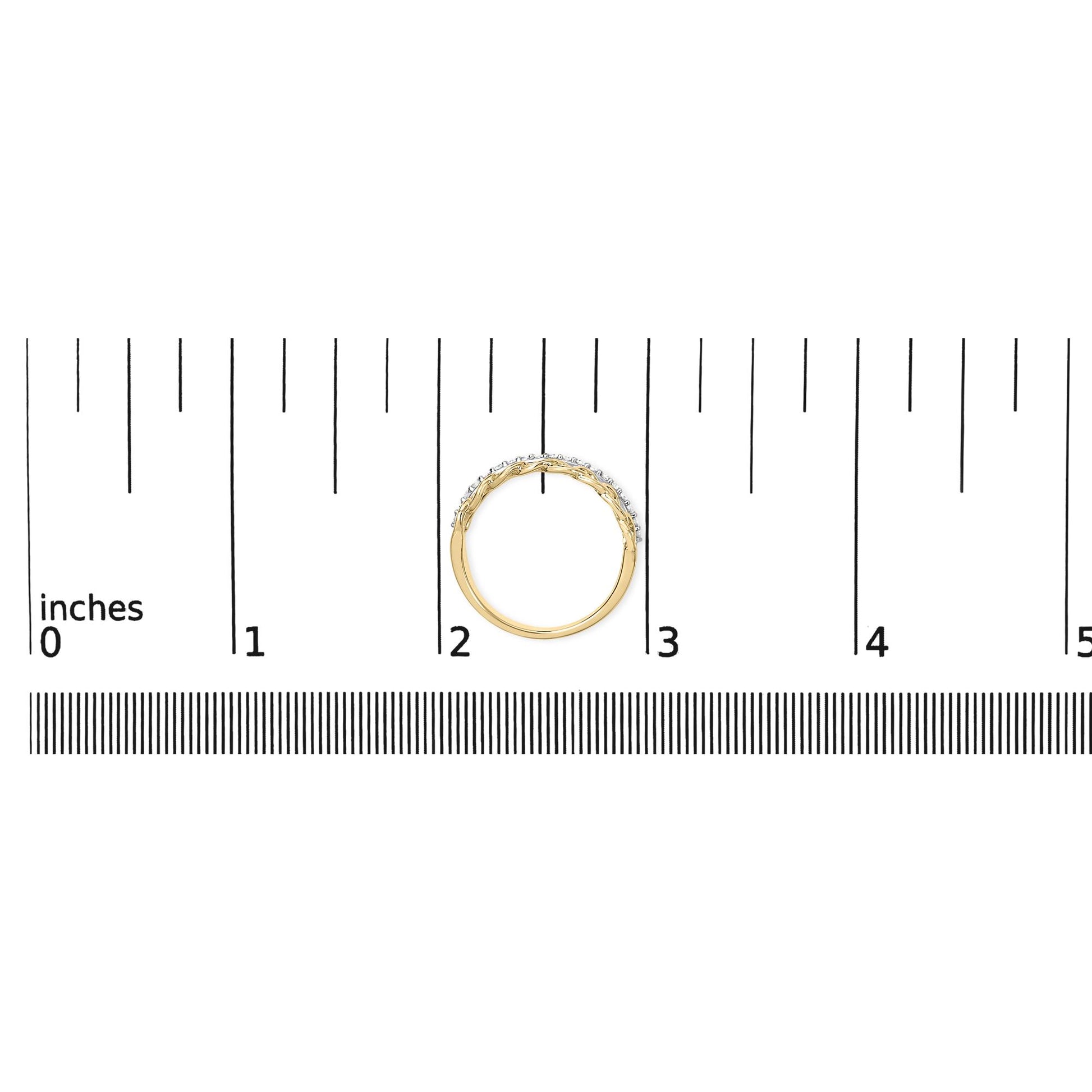 Top-down view of a yellow metal ring with a row of round white gemstones in shared prong setting, placed on a ruler for size reference.