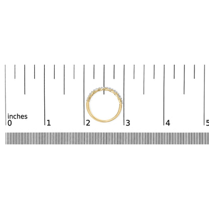 Top-down view of a yellow metal ring with a row of round white gemstones in shared prong setting, placed on a ruler for size reference.