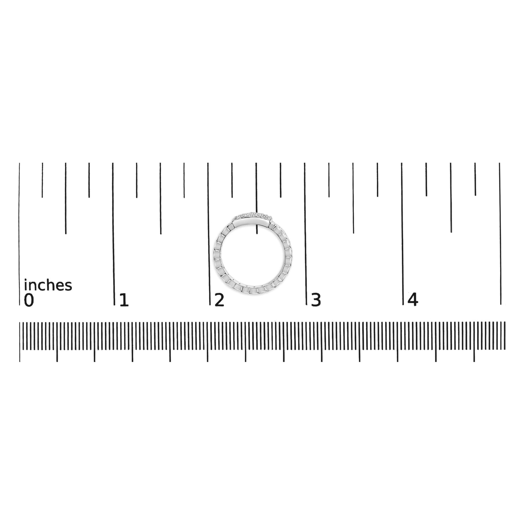 Top-down view of a white metal ring with small round white gemstones set in a prong setting, placed on a ruler for size reference.