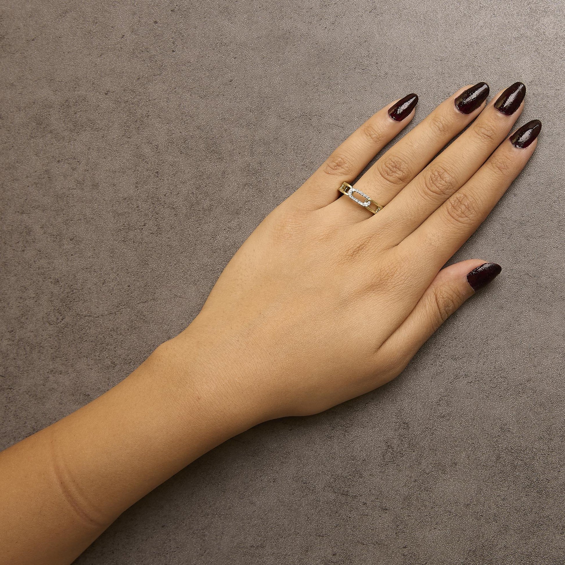 Yellow metal ring with round white gemstones in channel setting, worn on hand, top-down angle.