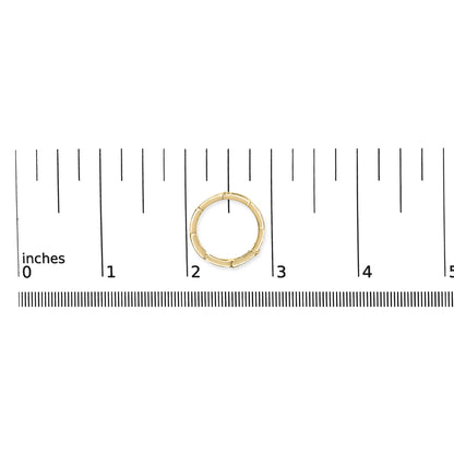 Top-down view of a yellow metal ring with round white gemstones set in a channel, placed on a ruler for size reference.