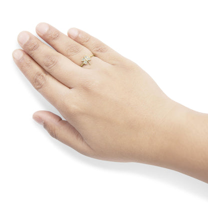 Close-up angled shot of a yellow ring with prong-set round white gemstones arranged in a floral design, worn on a model's finger.