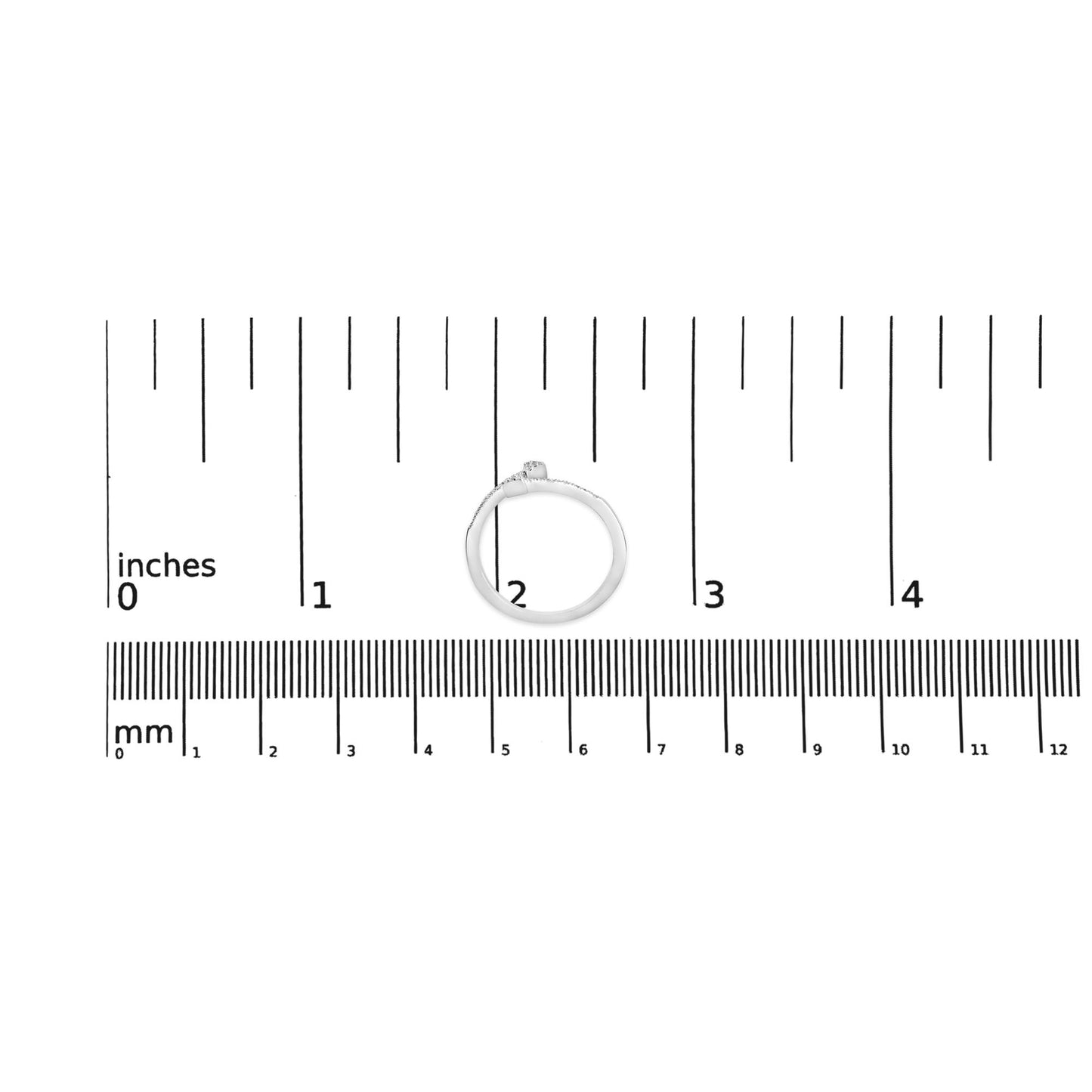 White metal ring with round white gemstones in prong settings placed on a ruler for size reference, top-down view.