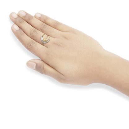 Yellow metal ring with white round gemstones in prong setting, worn on a model's hand, shot from above at an angle.