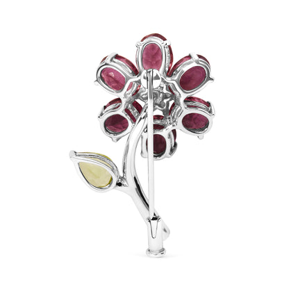 Back view of white metal flower-shaped brooch with pink oval and green pear-shaped gemstones, shown upright.