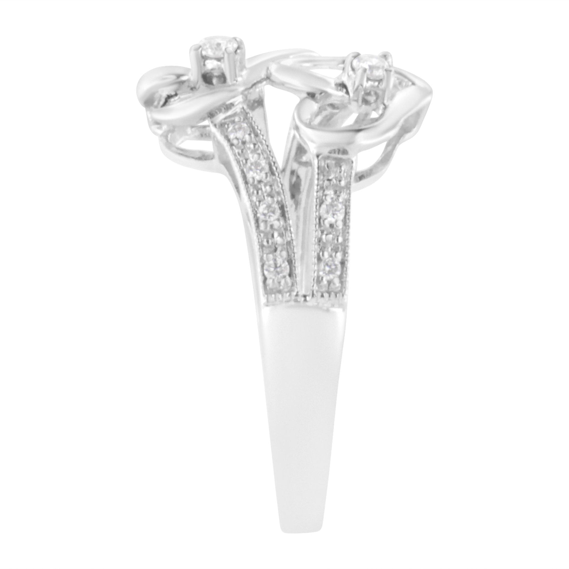 Front angle view of a white metal ring featuring two round white gemstones in prong settings and multiple round white gemstones in micro-pave settings along the band split.