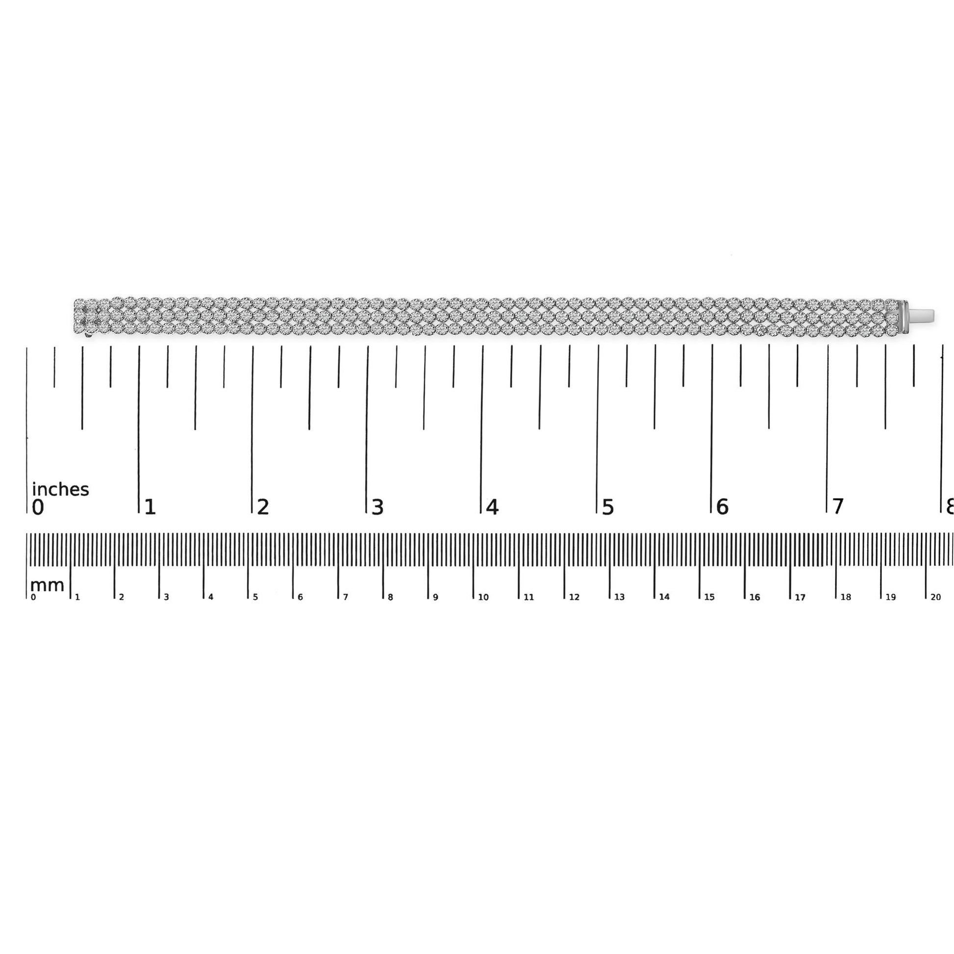 Straight-on shot of a white metal bracelet with multiple rows of round white gemstones in prong settings, displayed flat on a ruler for size reference.