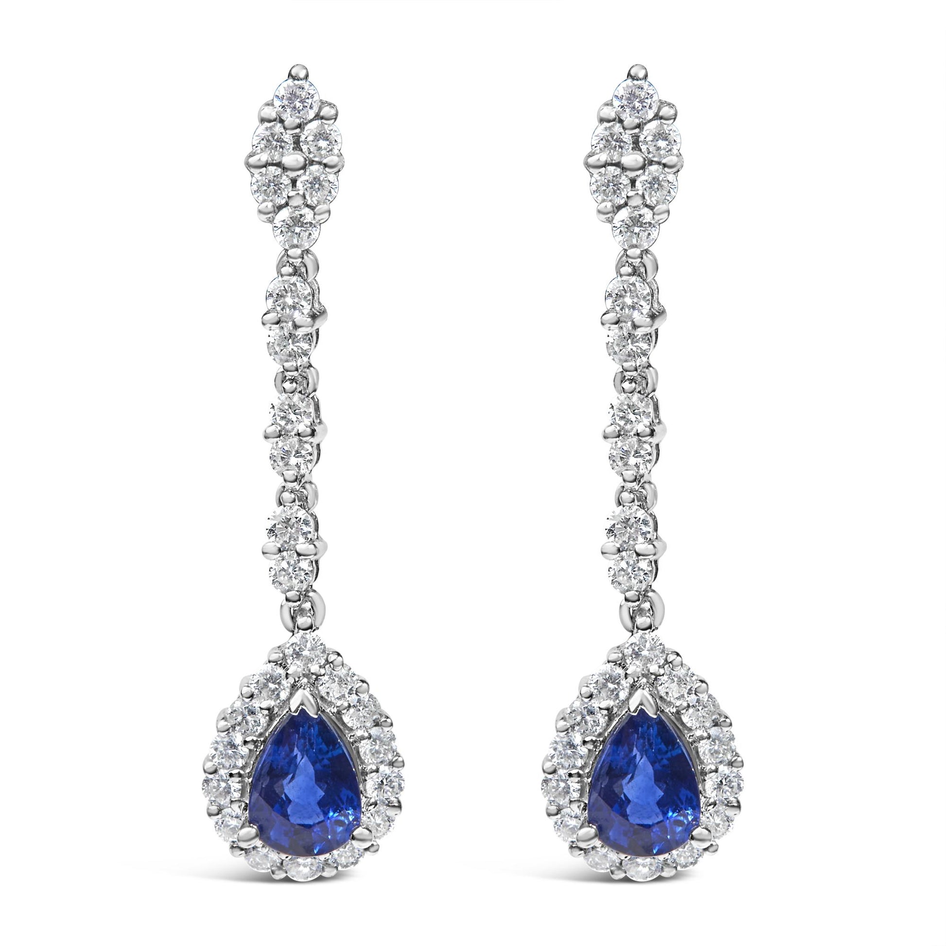 Front view of a pair of white metal drop earrings with round white gemstones in 4-prong settings along the length and a pear-shaped blue gemstone surrounded by round white gemstones at the bottom.