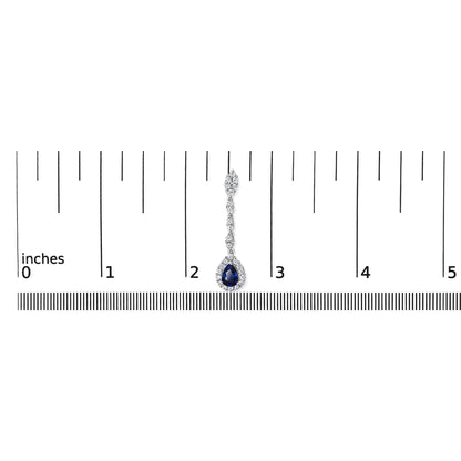 Single white metal earring with round white gemstones and a pear-shaped blue gemstone, shown from front on against a ruler for size reference.