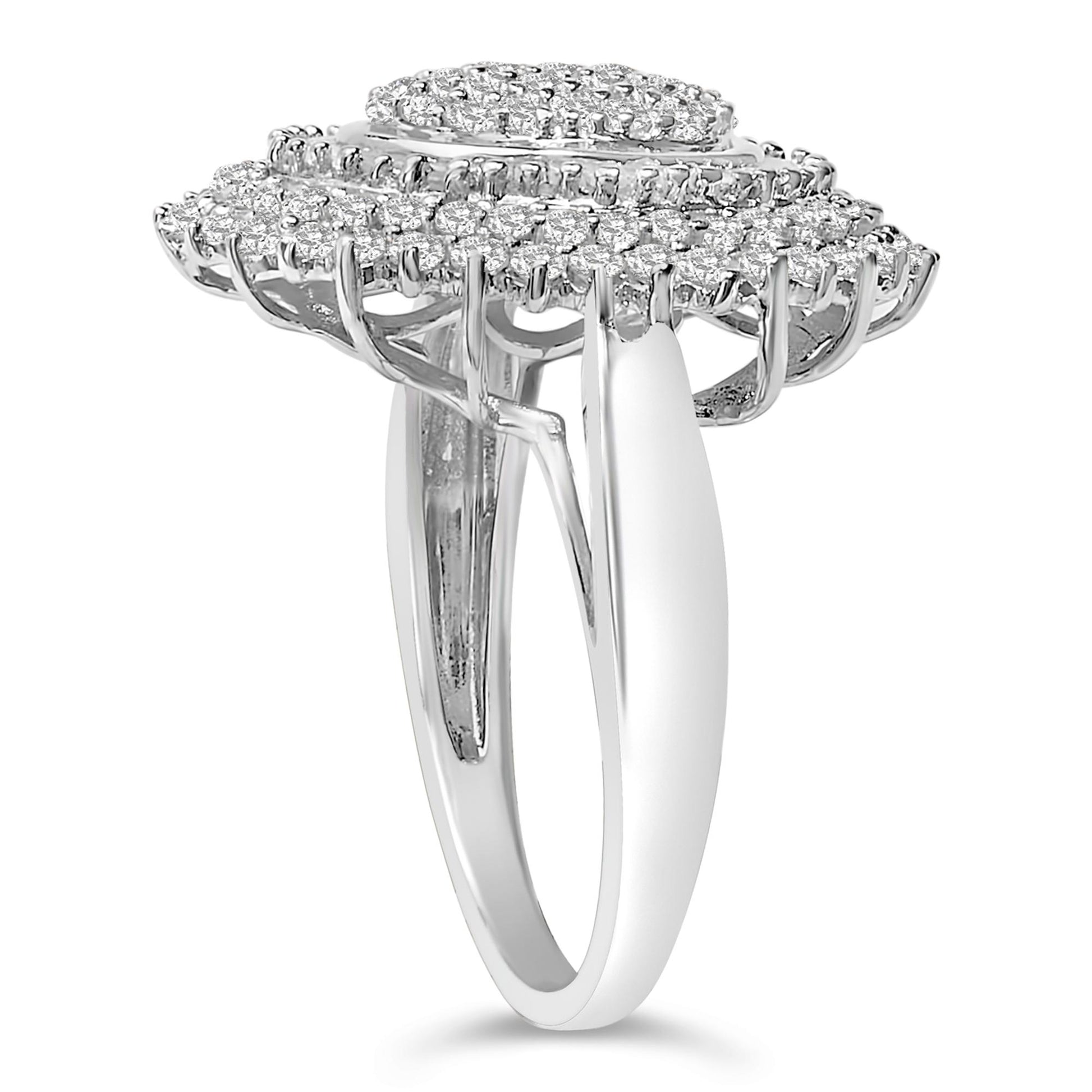 Close-up side angle of a white metal ring featuring a raised oval-shaped top with multiple round white gemstones in prong settings and baguette white gemstones in channel settings.
