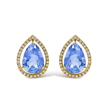 Close-up front angle of yellow metal earrings featuring large pear-shaped blue gemstones surrounded by a halo of small round white gemstones in prong settings.