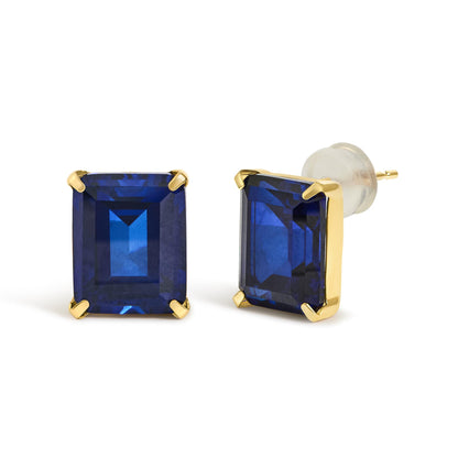 Close-up front and side angle of a pair of yellow metal stud earrings with large rectangular blue gemstones in four-prong settings, shown on a white background.