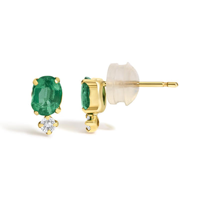 Close-up front and side view of a pair of yellow metal stud earrings featuring oval green gemstones set in four-prong settings above round white gemstones also set in four-prong settings, shown on a white background.