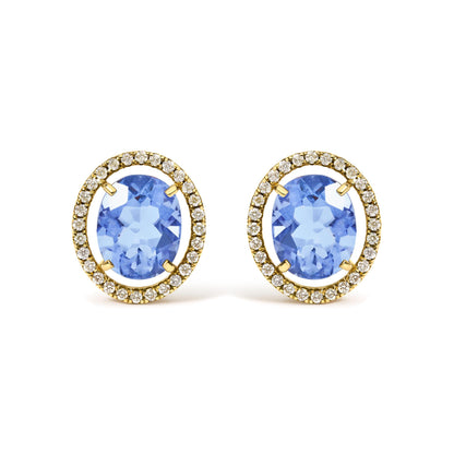 Close-up front view of yellow metal earrings featuring large oval blue gemstones at the center, surrounded by a halo of small round white gemstones in prong settings.