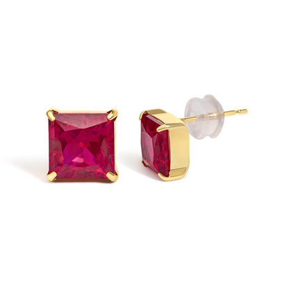 Close-up front and side angle of yellow metal earrings with square red gemstones in 4-prong settings shown on a white background.